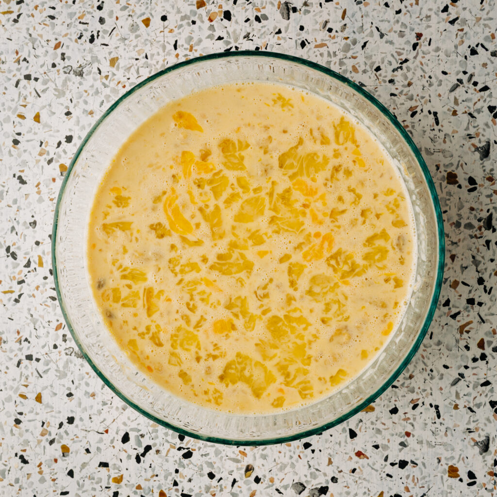 Mixing raw honey, melted butter, and eggs into the mashed banana base for a clean-ingredient batter.