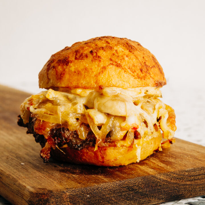 A single Bourbon Street slider with grass-fed beef, white cheddar, and honey-bourbon glaze on a white plate.