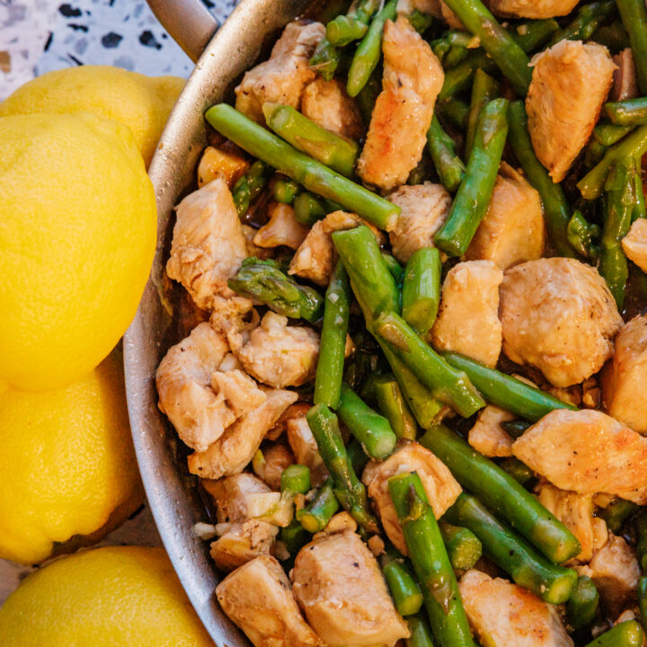 Lemon chicken and asparagus stir fry with garlic and bright lemon zest in a stainless steel pan