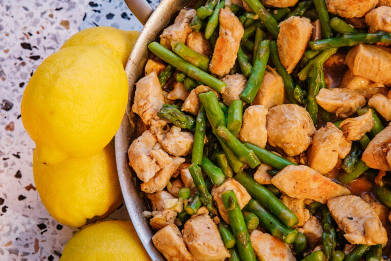 Lemon chicken and asparagus stir fry with garlic and bright lemon zest in a stainless steel pan