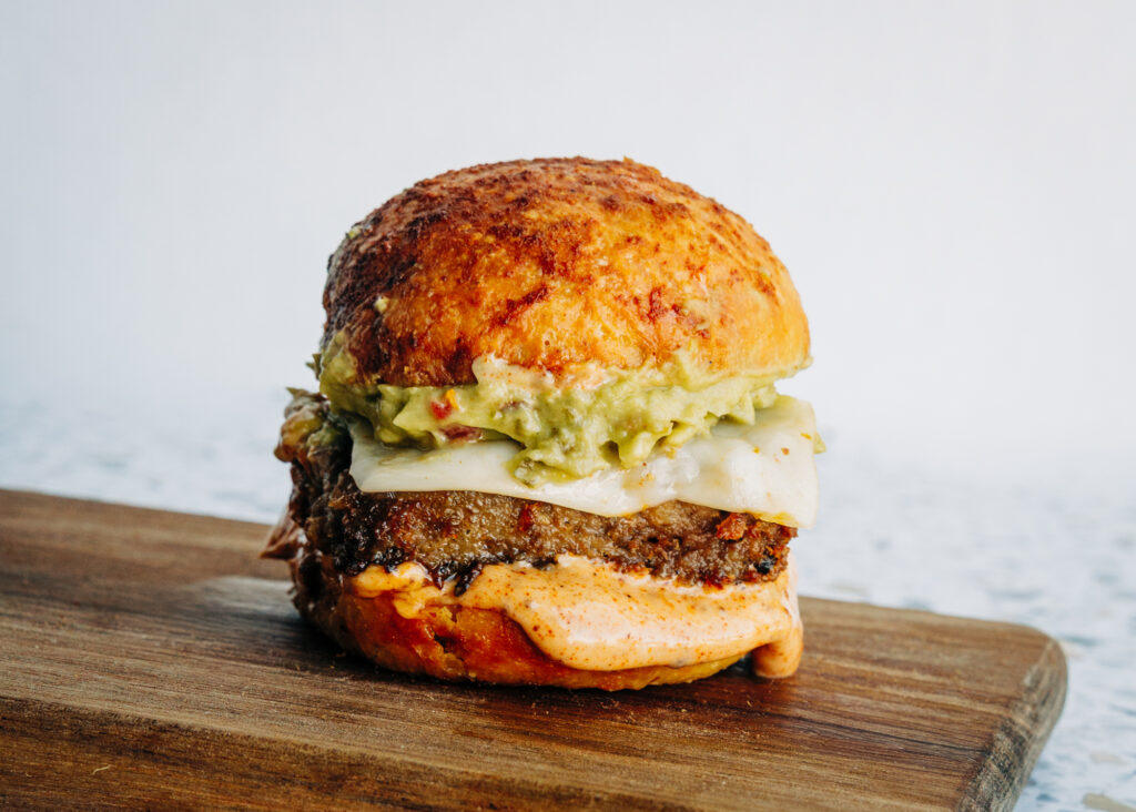 A finished Santa Fe slider with melted cheese, creamy homemade guacamole, and a drizzle of dye-free Santa Fe sauce.