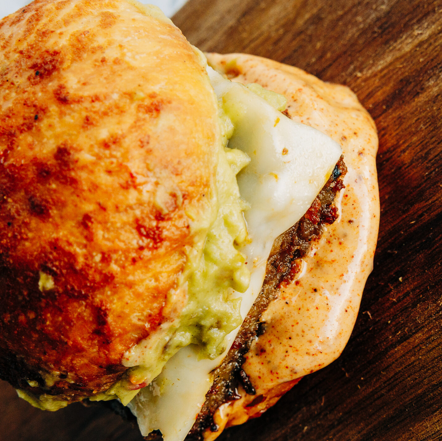 Close-up of a Santa Fe slider showing the layers of avocado and creamy, dye-free Santa Fe sauce on a toasted bun.