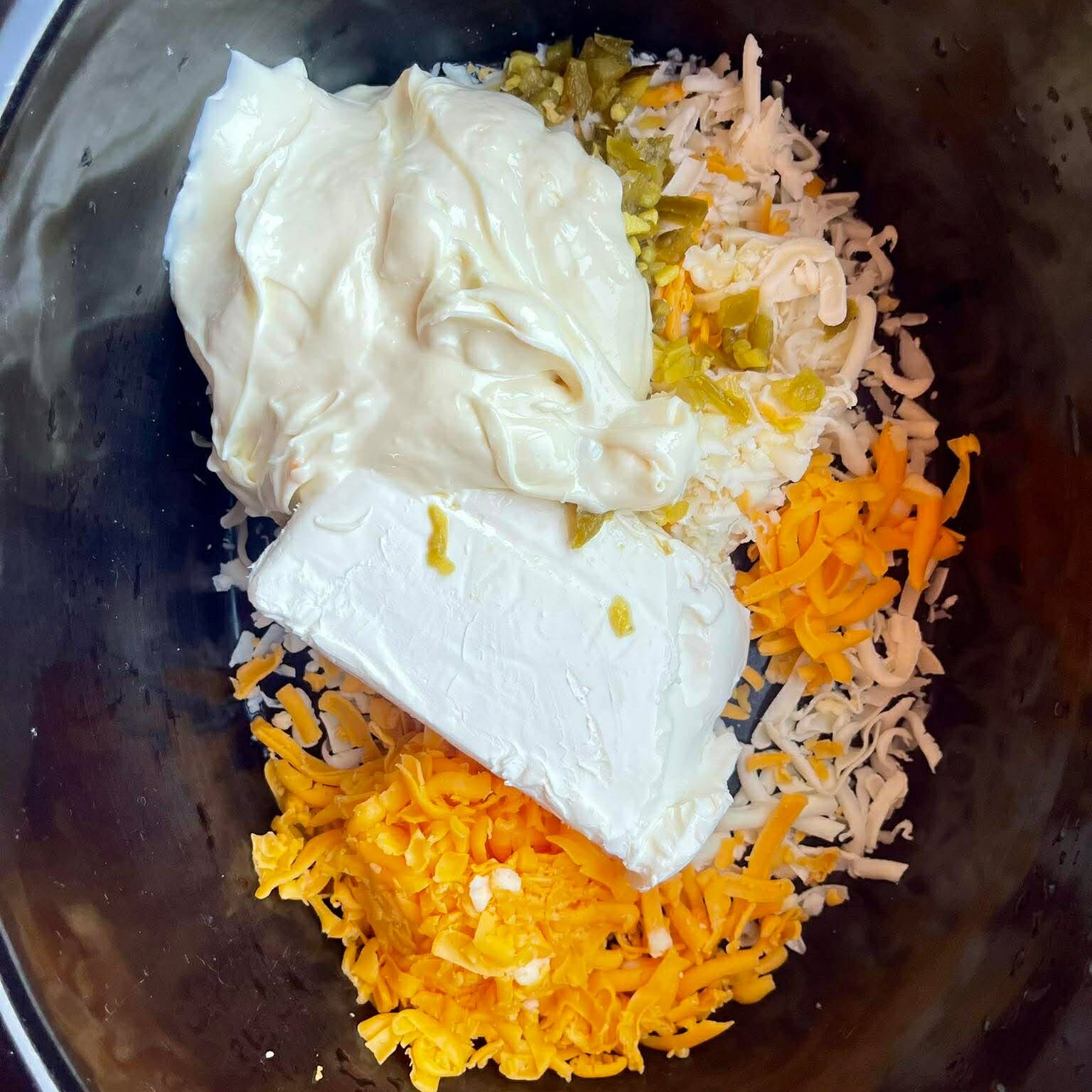 a crockpot filled with the ingredients for jalapeño popper dip