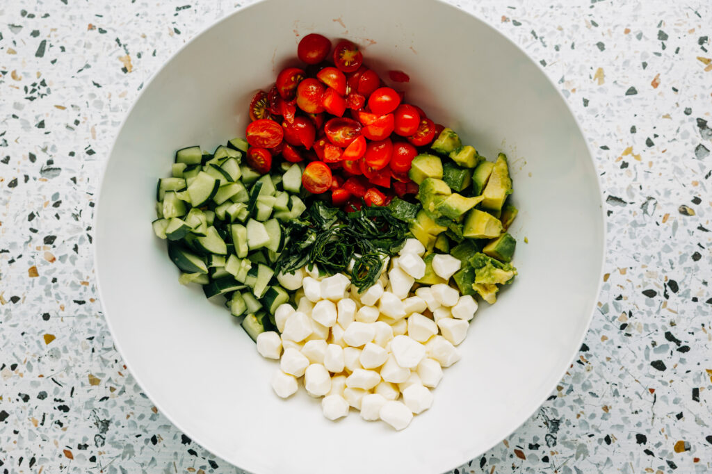 cucumber. tomatoes, avocados, and basil with mozzarella pearls, prepared to be a fresh garden salad