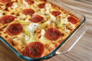 A chicken parmesan base topped with pizza toppings in a 9x13 on a wood table
