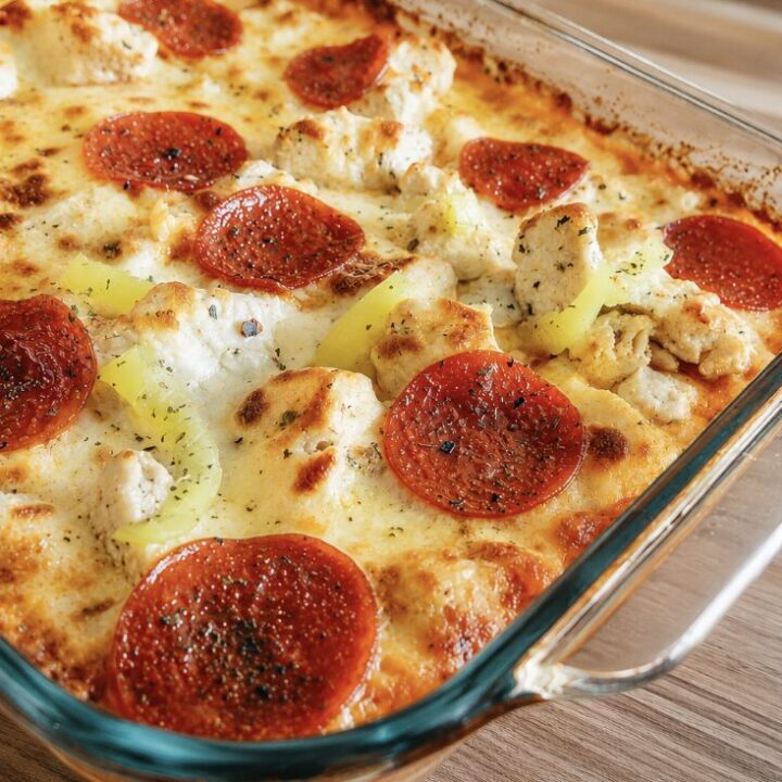 A chicken parmesan base topped with pizza toppings in a 9x13 on a wood table