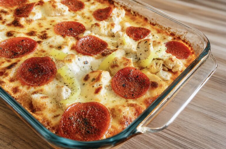 A chicken parmesan base topped with pizza toppings in a 9x13 on a wood table